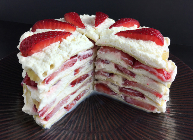 A plate holding Strawberry Cloud Crepe Cake with a piece cut out